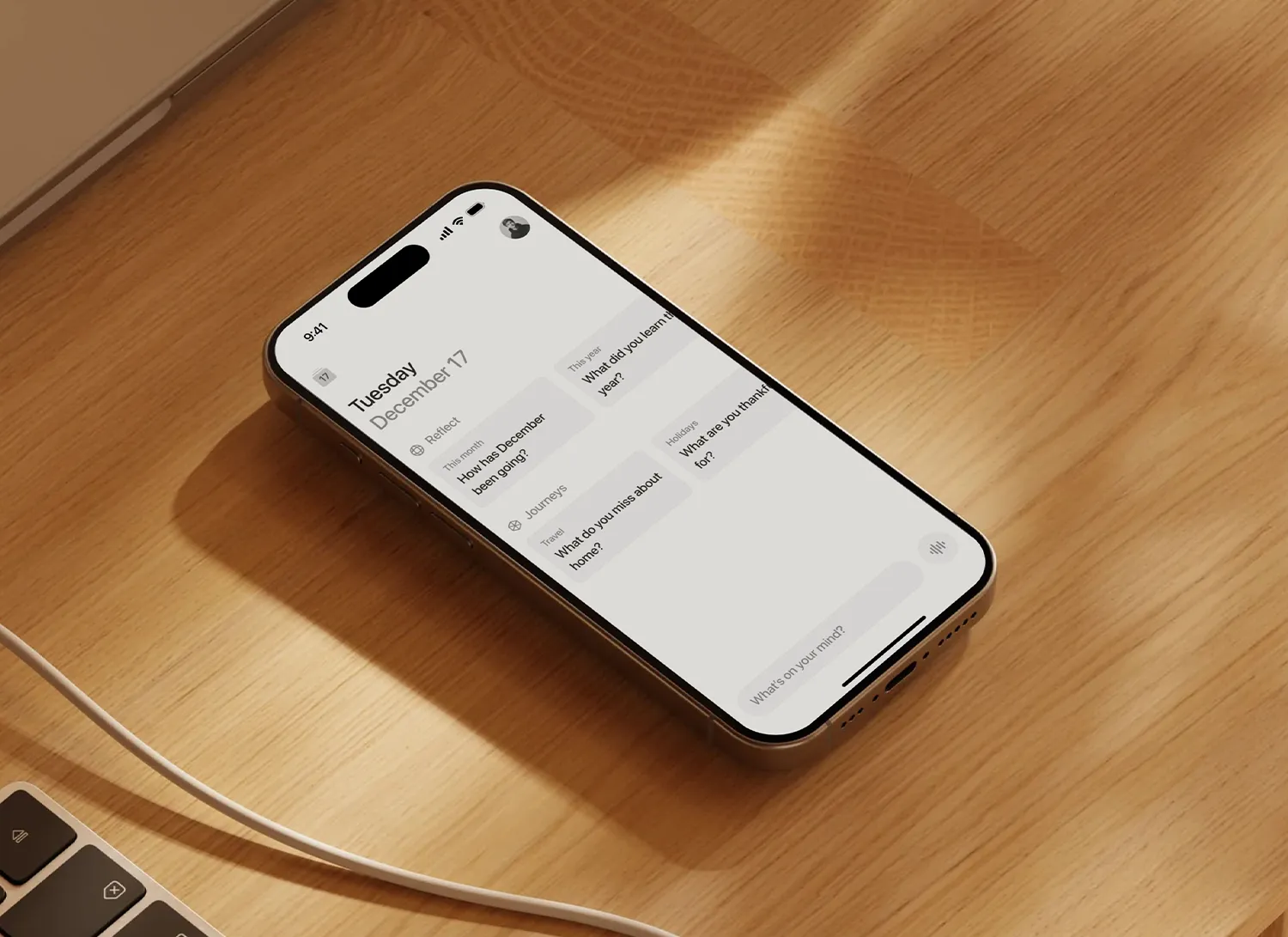 Téléphone posé sur une surface en bois affichant une application de réflexion quotidienne avec des questions sur le mois de décembre, l'année, les voyages et les vacances.